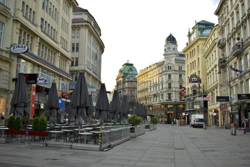 a street with tables and umbrellas on a city street at Pension a und a in Vienna
