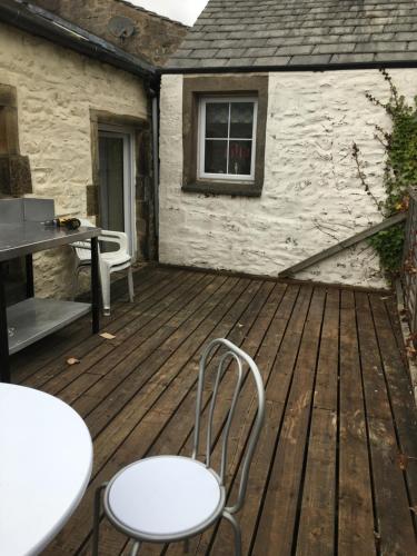 a wooden deck with chairs and a table and a building at Ingleton M'S Apartment in Ingleton