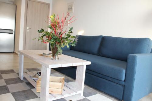 a blue couch and a table with a vase of flowers at Sappho Plomari in Plomarion