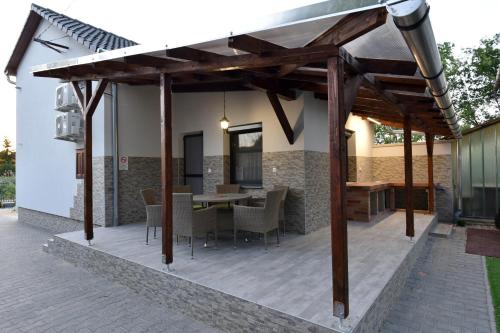 an outdoor dining area with a wooden pergola at Sirály Apartman in Hajdúnánás