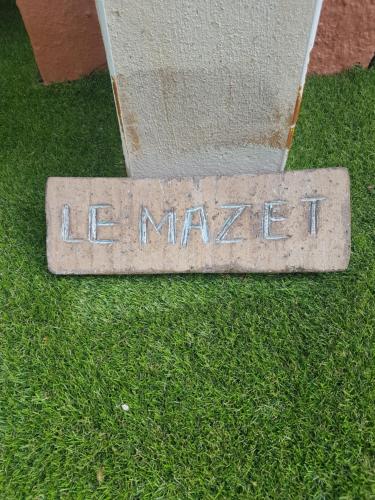 a stone sign in the grass next to a building at Hôtel-Restaurant "Chez Carrière" in Aigues-Mortes