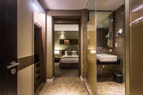 a bathroom with a bed and a sink and a mirror at Swiss-Garden Hotel Melaka in Melaka