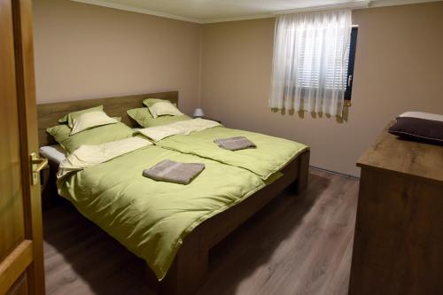 a bedroom with a bed with green sheets and pillows at Sirály Apartman in Hajdúnánás