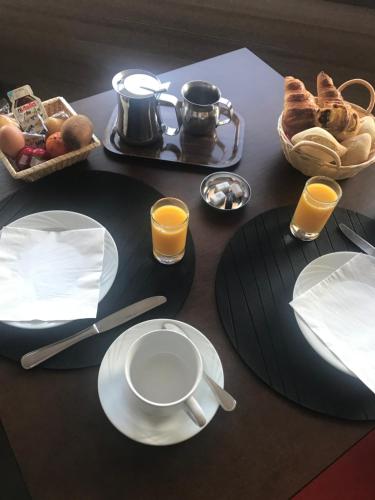 a table with plates of food and cups of orange juice at Hôtel Restaurant le Panorama in Évian-les-Bains