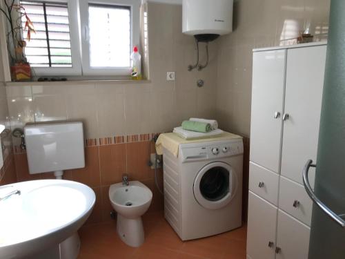 a bathroom with a washing machine and a toilet at Apartments Mirna with parking in Lovran
