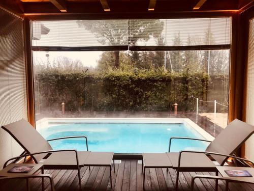 a swimming pool with chairs and a large window at Villa Abbondanzi Resort in Faenza