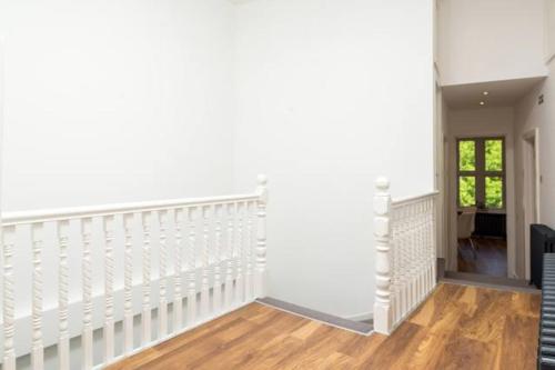 a white staircase in a living room with wooden floors at Stunningly Luxurious London Apartment (MHB350) in London