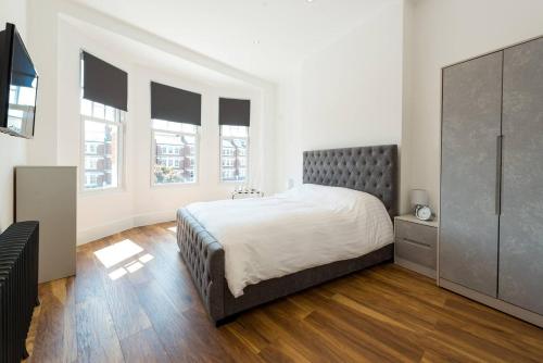 a bedroom with a bed and a dresser and windows at Stunningly Luxurious London Apartment (MHB350) in London