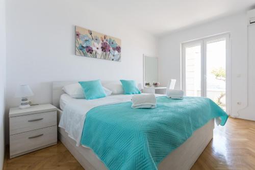 a white bedroom with a large bed with blue sheets at Apartment Jakov i Lucija in Dubrovnik