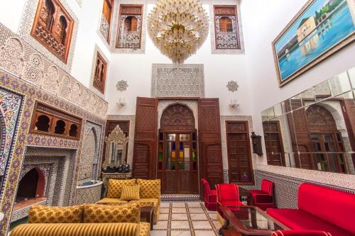 a living room with red chairs and a fireplace at Riad Fes Andalucia in Fès