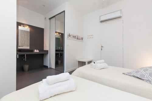 - une chambre blanche avec 2 lits et un miroir dans l'établissement Nature 2 pièces 3 étoiles calme plein centre cannes 5 mn des plages et Palais, à Cannes