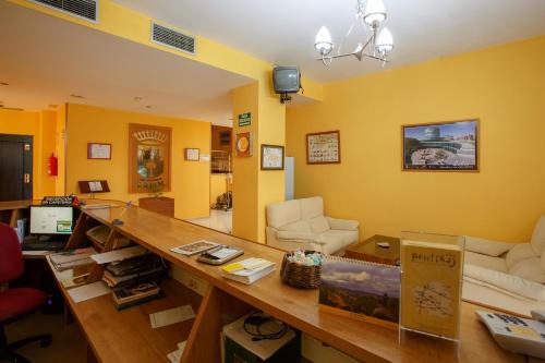 a living room with yellow walls and a wooden table at Hotel Restaurante Pontiñas in Lalín