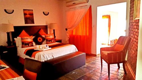 a bedroom with a large bed and a chair at Boschdal Upmarket Guesthouse in Rustenburg