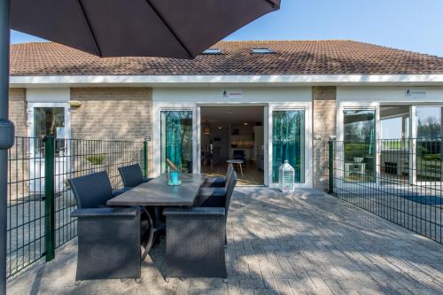 a patio with a table and chairs and an umbrella at Hansa watersport & recreatie in Wilhelminadorp