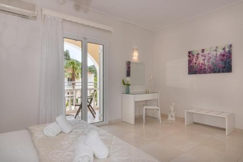 a white bedroom with a bed and a desk and a window at Edelweiss Hotel in Argasi