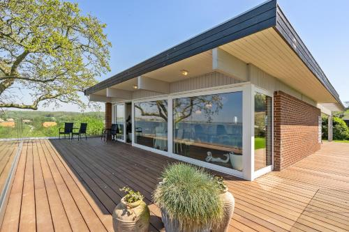 a house with a wooden deck with glass doors at Fjordhuset in Broager