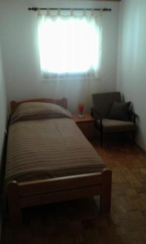 a bedroom with a bed and a chair and a window at Apartmani Tijano in Krnica