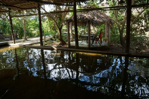 a pool of water with a pavilion and a table at mekong floating market Nam Giang homestay in Cai Be