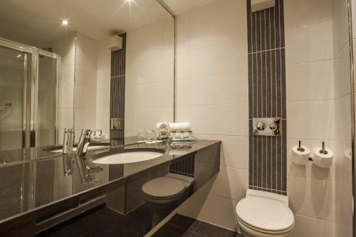 a bathroom with a sink and a toilet and a mirror at Skeffington Arms Hotel in Galway