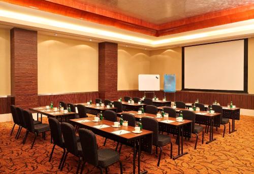 a conference room with tables and chairs and a screen at Novotel Mumbai Juhu Beach in Mumbai