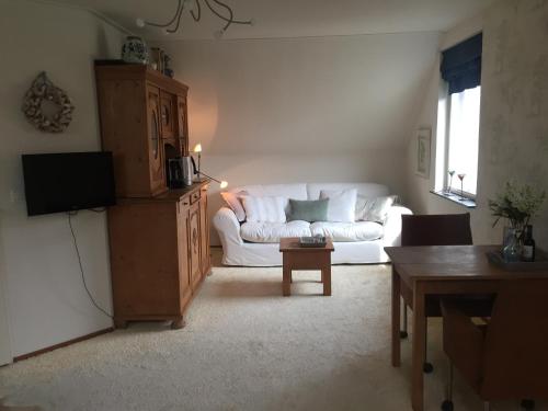 een woonkamer met een witte bank en een tafel bij B&B De Koraal in Emmen