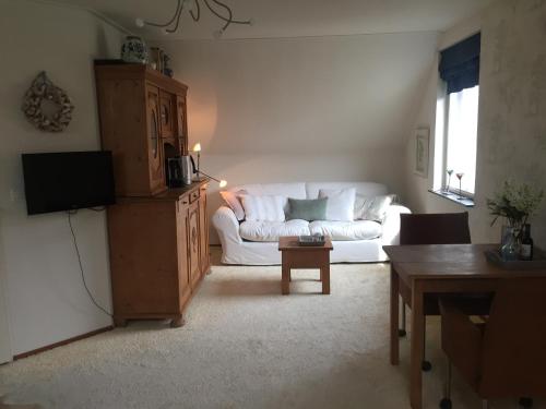 a living room with a white couch and a table at B&B De Koraal in Emmen