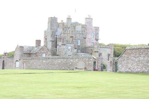 an old castle with a grass field in front of it at Harbour House Bed & Breakfast - Wick in Wick