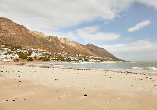 a beach with a town and mountains in the background at First Group Cape Gordonia in Gordonʼs Bay