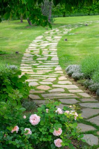 a stone path in a garden with pink roses at Borgo Argiano in Castelnuovo Berardenga