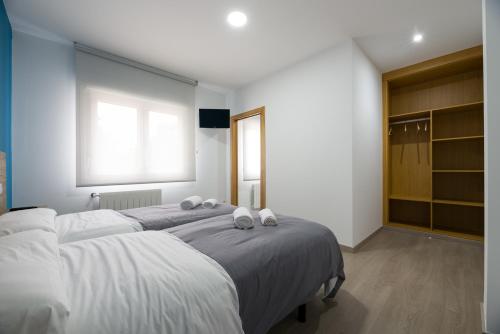 a bedroom with two beds with white sheets and a window at A Chousa in Arzúa