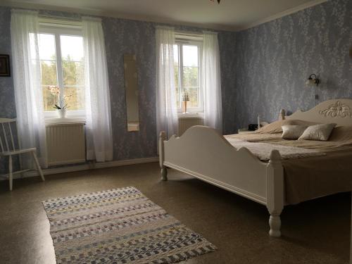 a bedroom with a white bed and two windows at Råshults Gård in Vimmerby