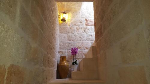 an alley with a vase and a vase with purple flowers at Torres Suite in Polignano a Mare