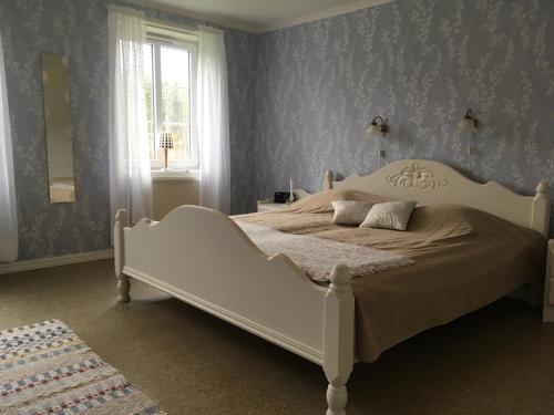 a white bed in a blue bedroom with a window at Råshults Gård in Vimmerby
