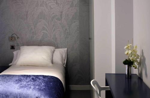 a bedroom with a bed and a table and a wall at Hostal Averroes in Burgos