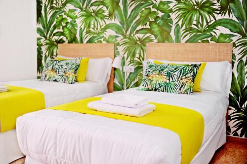 2 camas en una habitación de color amarillo y blanco en Los Escondidos Ibiza, en Playa d'en Bossa