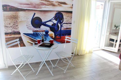 a table and chairs in a room with a painting on the wall at Sappho Plomari in Plomarion