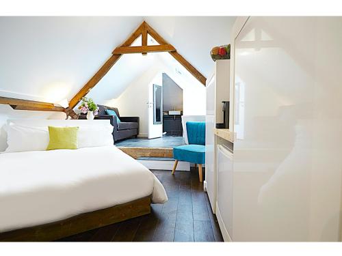 um quarto com uma cama branca e uma cadeira azul em Live & Let Live Inn em Woodland
