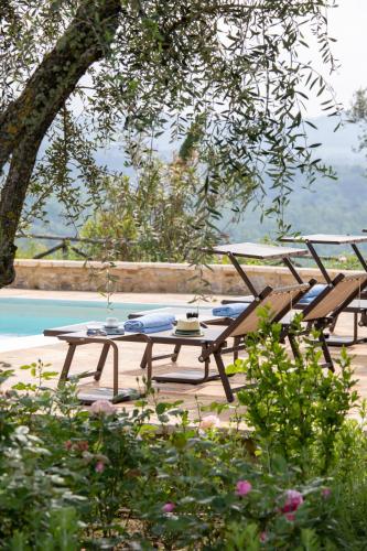 two picnic tables and chairs sitting next to a pool at Borgo Argiano in Castelnuovo Berardenga