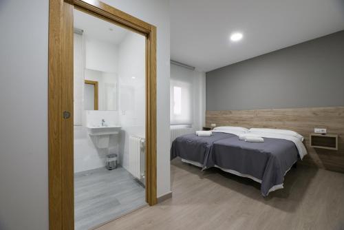 1 dormitorio con cama, lavabo y espejo en A Chousa, en Arzúa