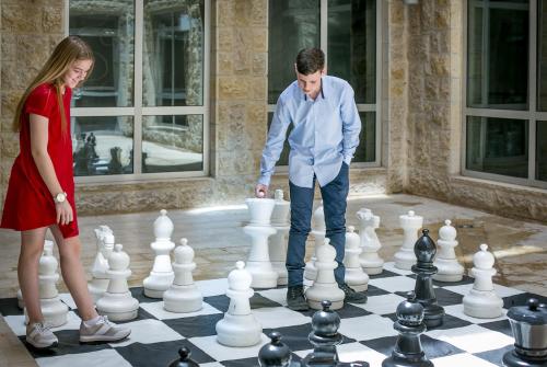 a man and a woman playing chess on a giant chessboard at Hotel Yehuda in Jerusalem