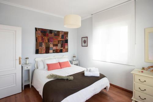 Un dormitorio blanco con una cama grande con almohadas rojas en Vivienda O Pombal, en Cambados