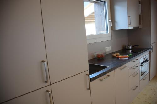 a kitchen with white cabinets and a window at Chalet Nr. 50 in Flühli