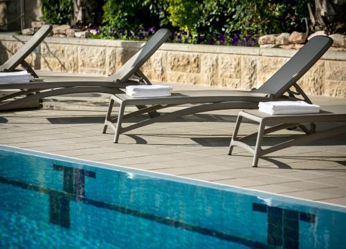two lounge chairs sitting next to a swimming pool at Hotel Yehuda in Jerusalem