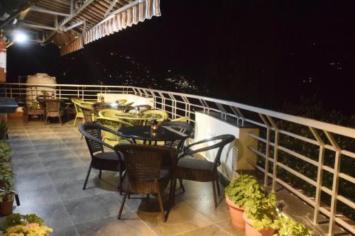a patio with tables and chairs on a balcony at night at Cloud 7 in Nainital