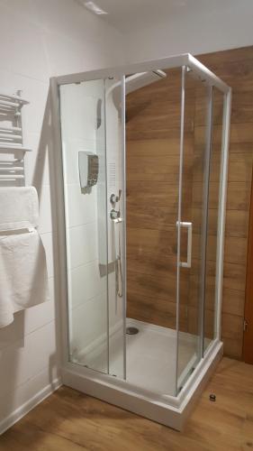 La salle de bains est pourvue d'une douche avec une porte en verre. dans l'établissement Gościnna Arkada, à Kleszczele