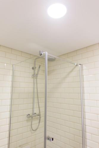 a shower in a bathroom with white tiles at Apartamentos Praça Amarela by Heart of Funchal in Funchal