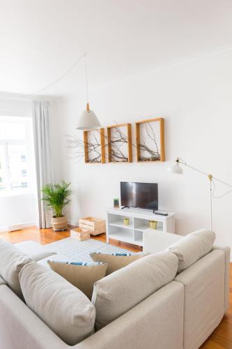 a white living room with a couch and a tv at Apartamentos Praça Amarela by Heart of Funchal in Funchal