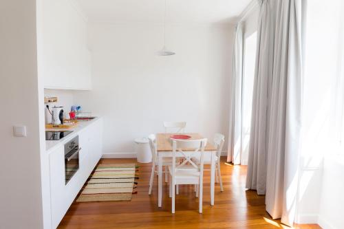 a kitchen with white walls and a table and chairs at Apartamentos Praça Amarela by Heart of Funchal in Funchal