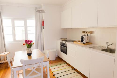 a kitchen with white cabinets and a table with flowers on it at Apartamentos Praça Amarela by Heart of Funchal in Funchal