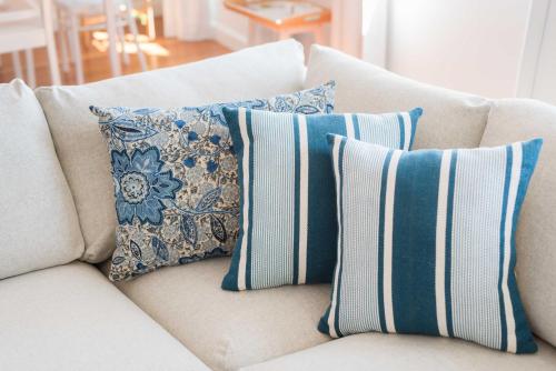 a white couch with blue and white pillows on it at Apartamentos Praça Amarela by Heart of Funchal in Funchal